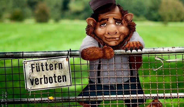 Dieses Bild zeigt einen Troll, der hinter einem Zaun steht und dem Betrachter frontal zugewendet ist. Auf der linken Seite ist ein Schild mit der Aufschrift "Füttern verboten" an dem Zaun festgemacht.